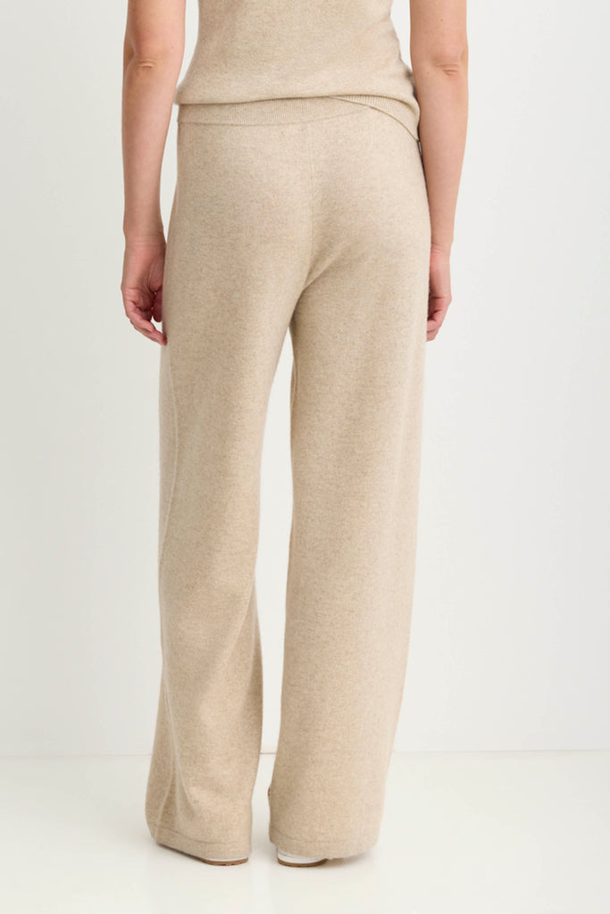 A person shown from the back wearing light beige wide-leg knit pants and a matching top against a plain white studio background.